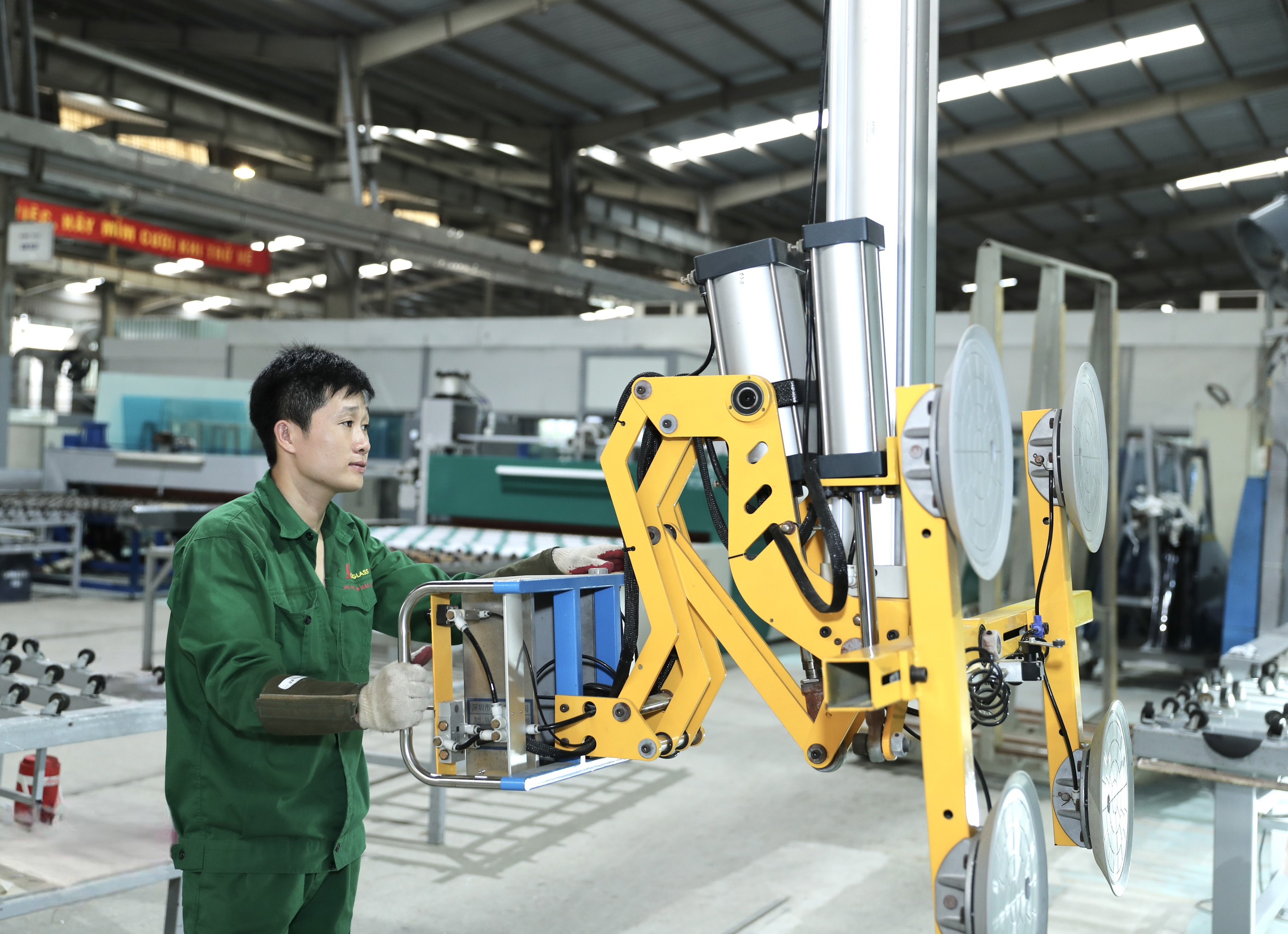 Nhân viên nhà máy thao tác với thiết bị nâng và xử lý kính
